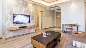 Une chambre d’hôtel moderne avec un mur en marbre, un téléviseur à écran plat, une table basse en bois et un canapé.