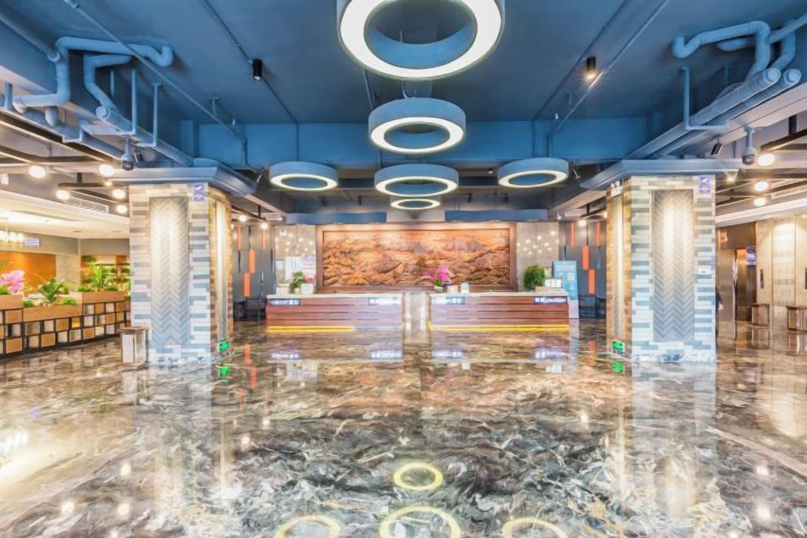 A hotel lobby with a marble floor, reception desk, and circular ceiling lights.