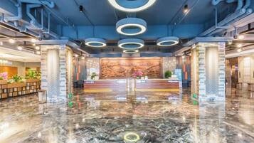 A hotel lobby with a marble floor, reception desk, and circular ceiling lights.