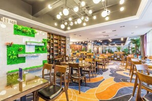 A modern library with bookshelves, tables, and chairs arranged for reading and dining. - Rimei Hotel (Foshan Sanshui New Power) (Foshan)