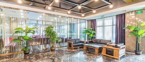 A lobby with a marble floor, seating area, and potted plants.