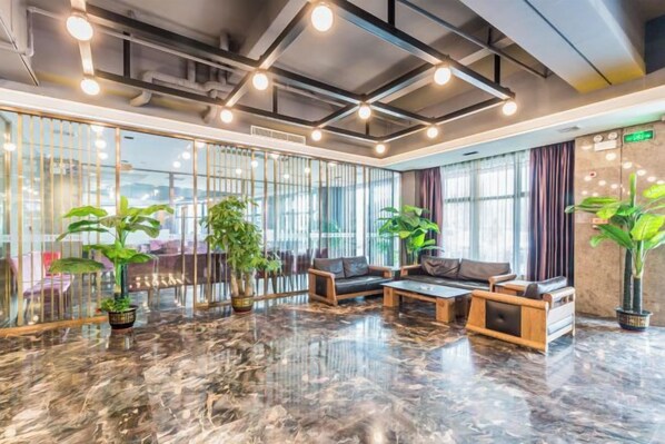 A lobby with a marble floor, seating area, and potted plants.