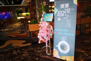 A hotel lobby with a reception desk, seating area, and a large screen. - Rimei Hotel (Foshan Sanshui New Power) (Foshan)