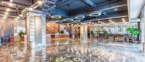 Un hall d’entrée spacieux, doté d’un sol en marbre poli, d’un comptoir de réception et d’un éclairage moderne.