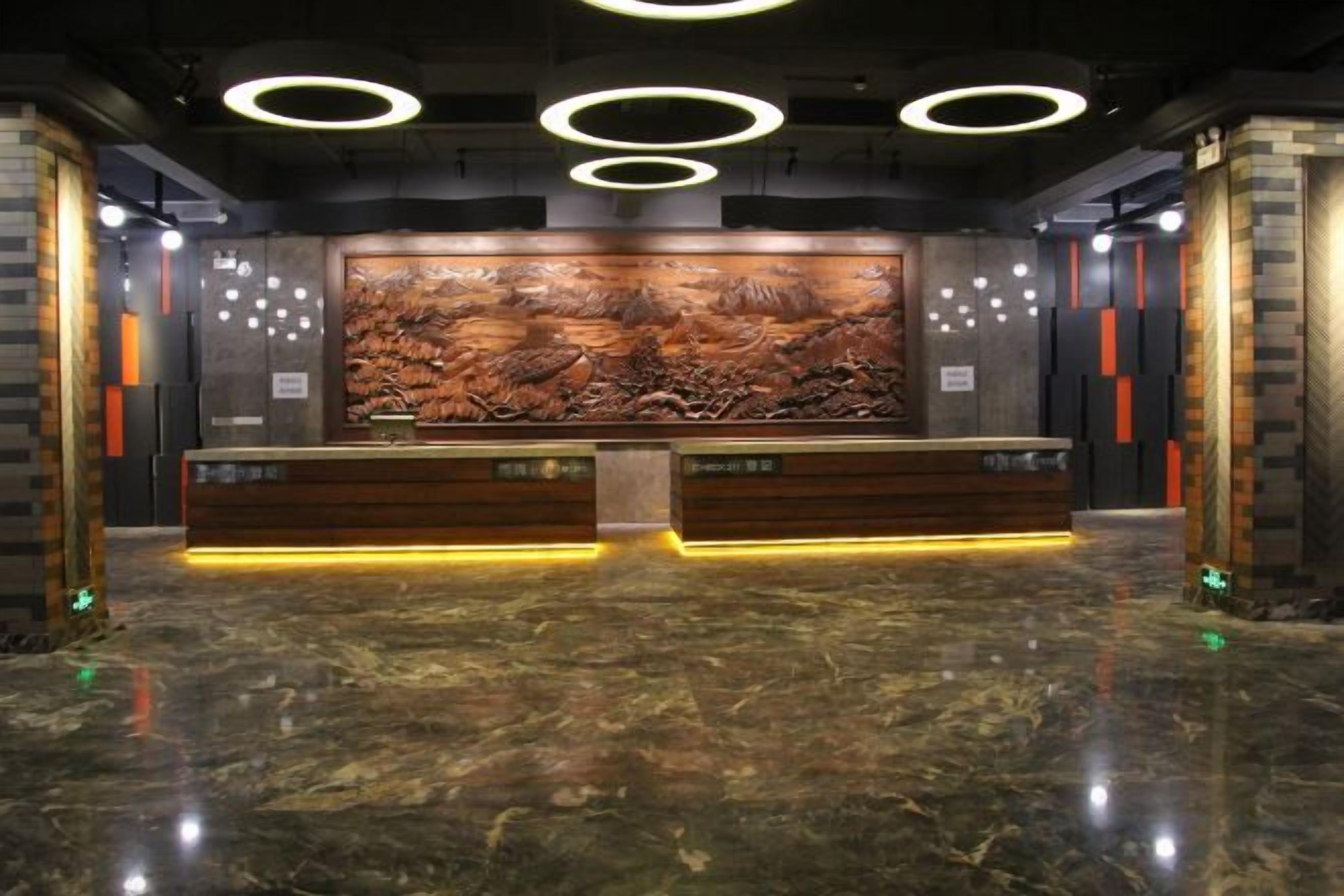 Un área de recepción con piso de mármol, una mesa de recepción y un gran mural en la pared.
