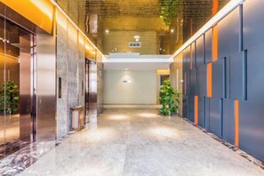 A hallway with a marble floor, a staircase, and a wall with vertical orange accents. - Rimei Hotel (Foshan Sanshui New Power) (Foshan)