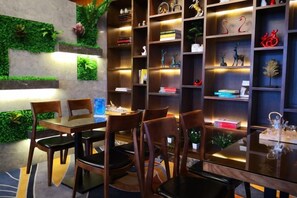 A dining area with a table and chairs, surrounded by bookshelves with various items.