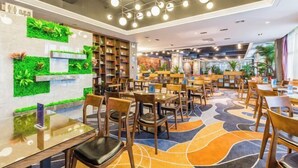 Interior moderno de restaurante con zona de estar central, jardines verticales verdes y piso estampado.