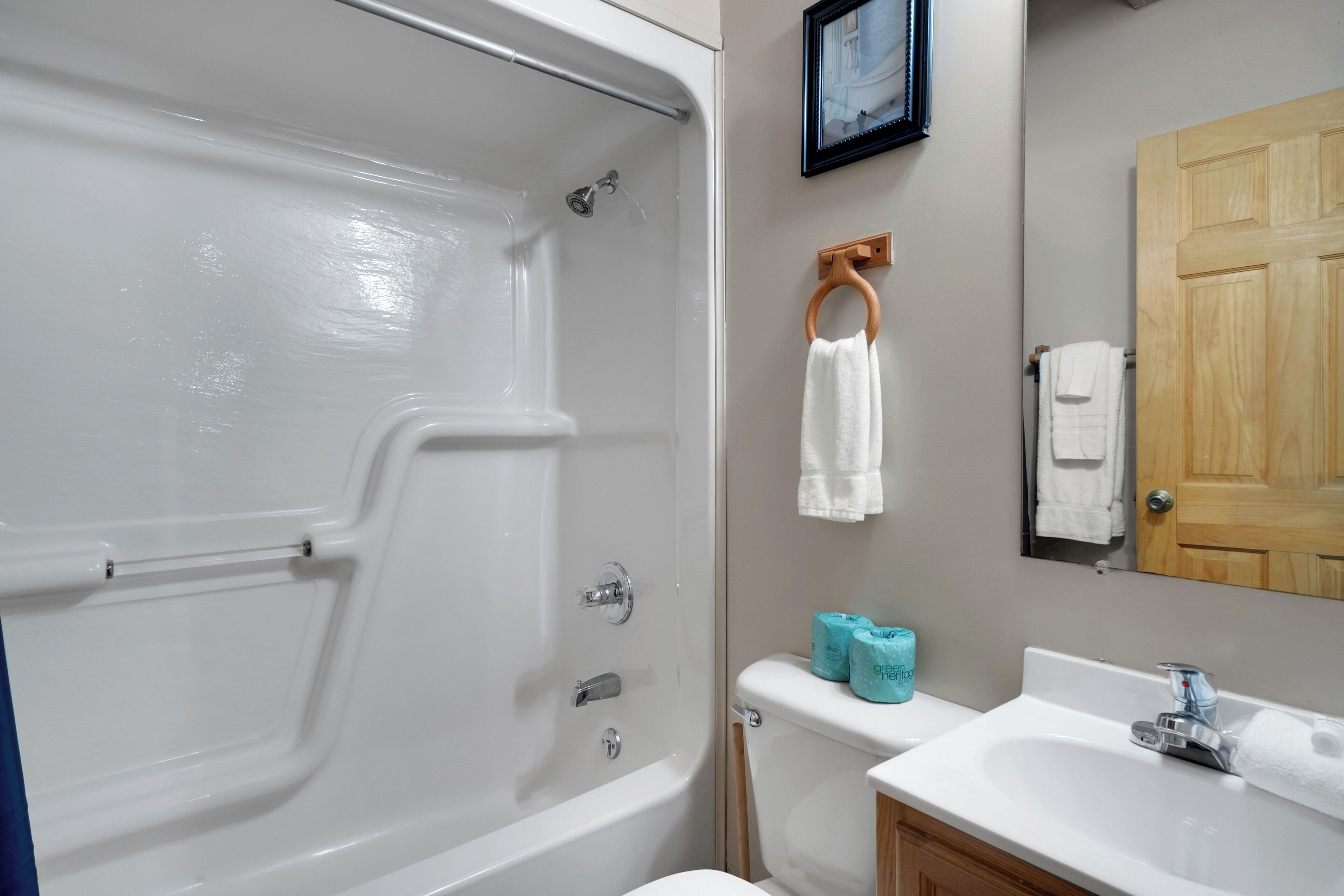 A bathroom with a bathtub, toilet, sink, and wooden door.