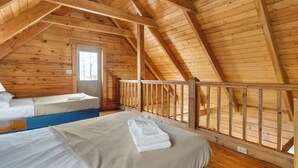 Una cabaña de madera con dos camas, un balcón y una ventana.