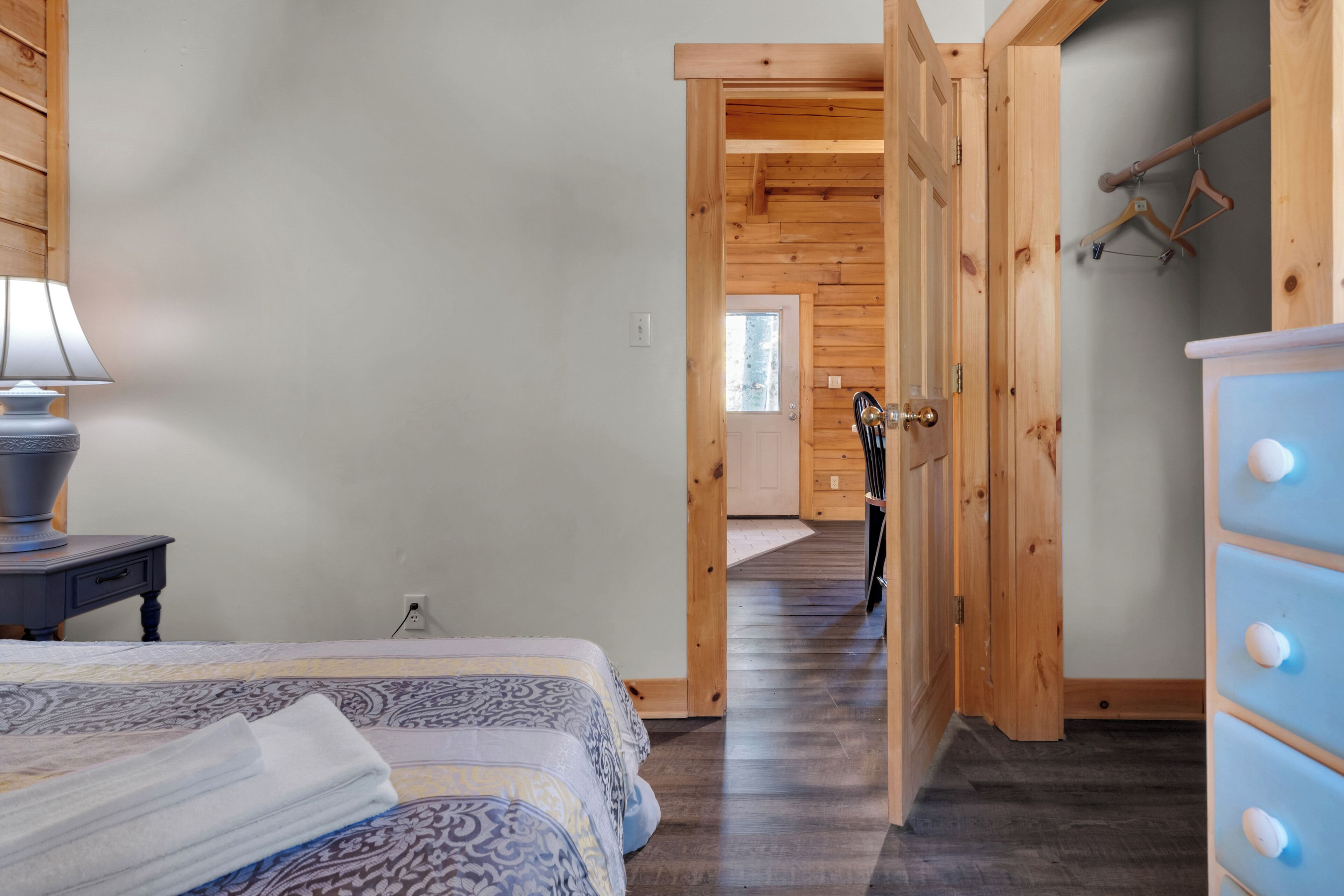 A bedroom with a bed, a dresser, and a lamp.