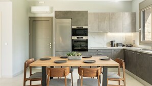 Eine moderne Küche mit eingebautem Backofen, einem Esstisch mit Stühlen und einer Arbeitsplatte mit Kaffeemaschine.