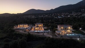 Ein großes, modernes Haus mit mehreren Bereichen, einem Swimmingpool und Blick auf eine gebirgige Landschaft.