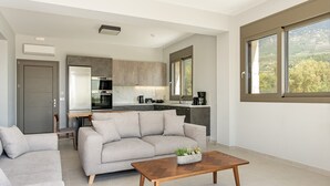 Ein modernes Wohnzimmer mit einem grauen Sofa, einem Holztisch und einer Küche im Hintergrund.