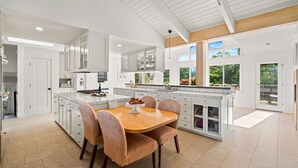 A spacious kitchen with white cabinetry, a central island, and a dining area with a wooden table and chairs.