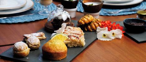 A table set with various pastries, desserts, and beverages, suggesting a breakfast or brunch setting.