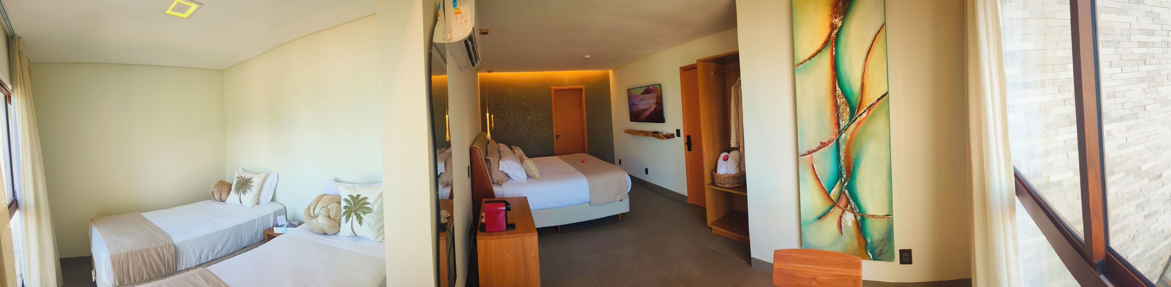 A hotel room with a bed, a desk, a chair, a painting, and a window.