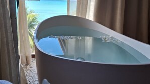 Una bañera con vista al océano a través de una ventana.