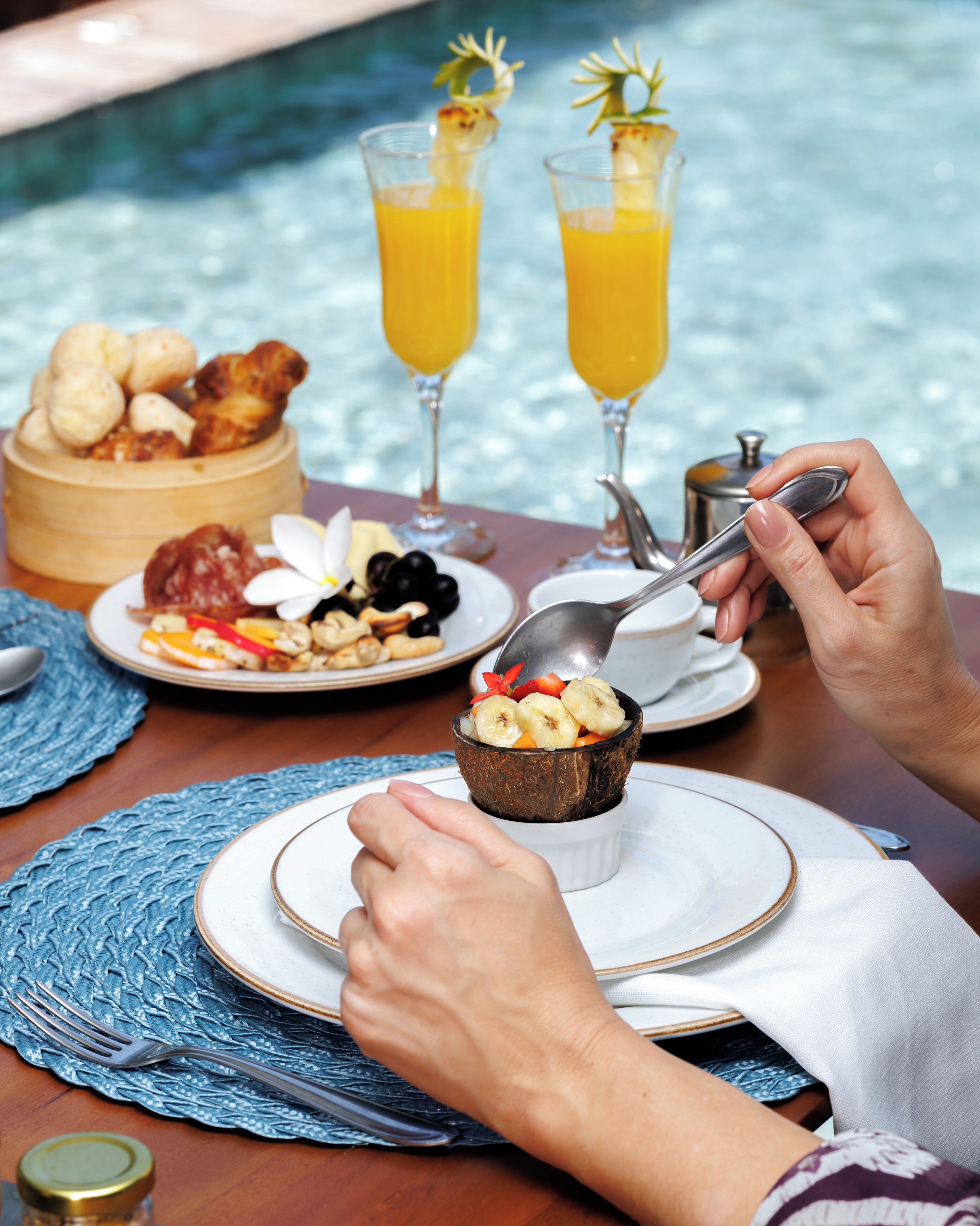 A dining table with plates of food, a bowl of dessert, and two glasses of orange juice.