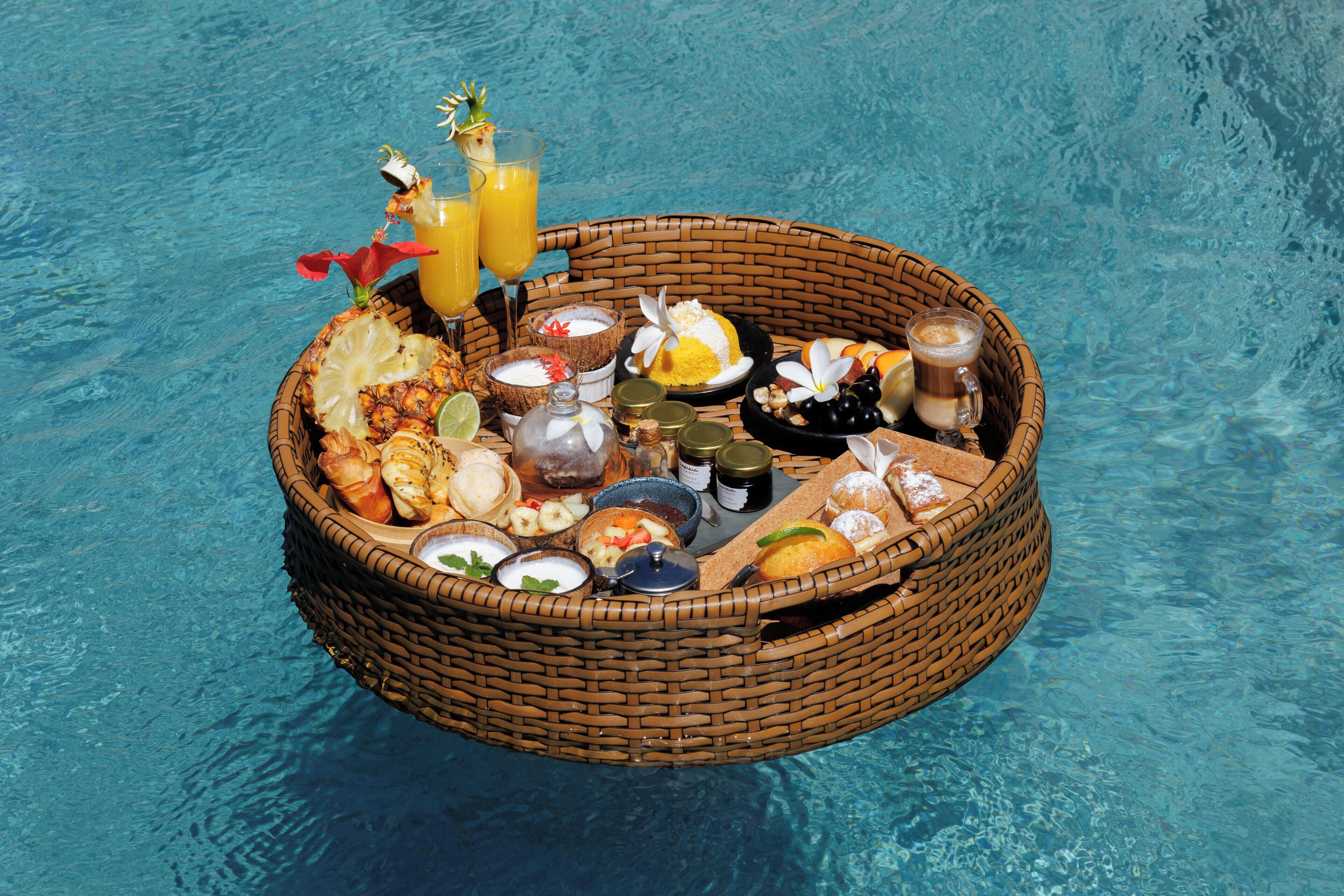 Una cesta flotante con comida y bebidas sobre una piscina.