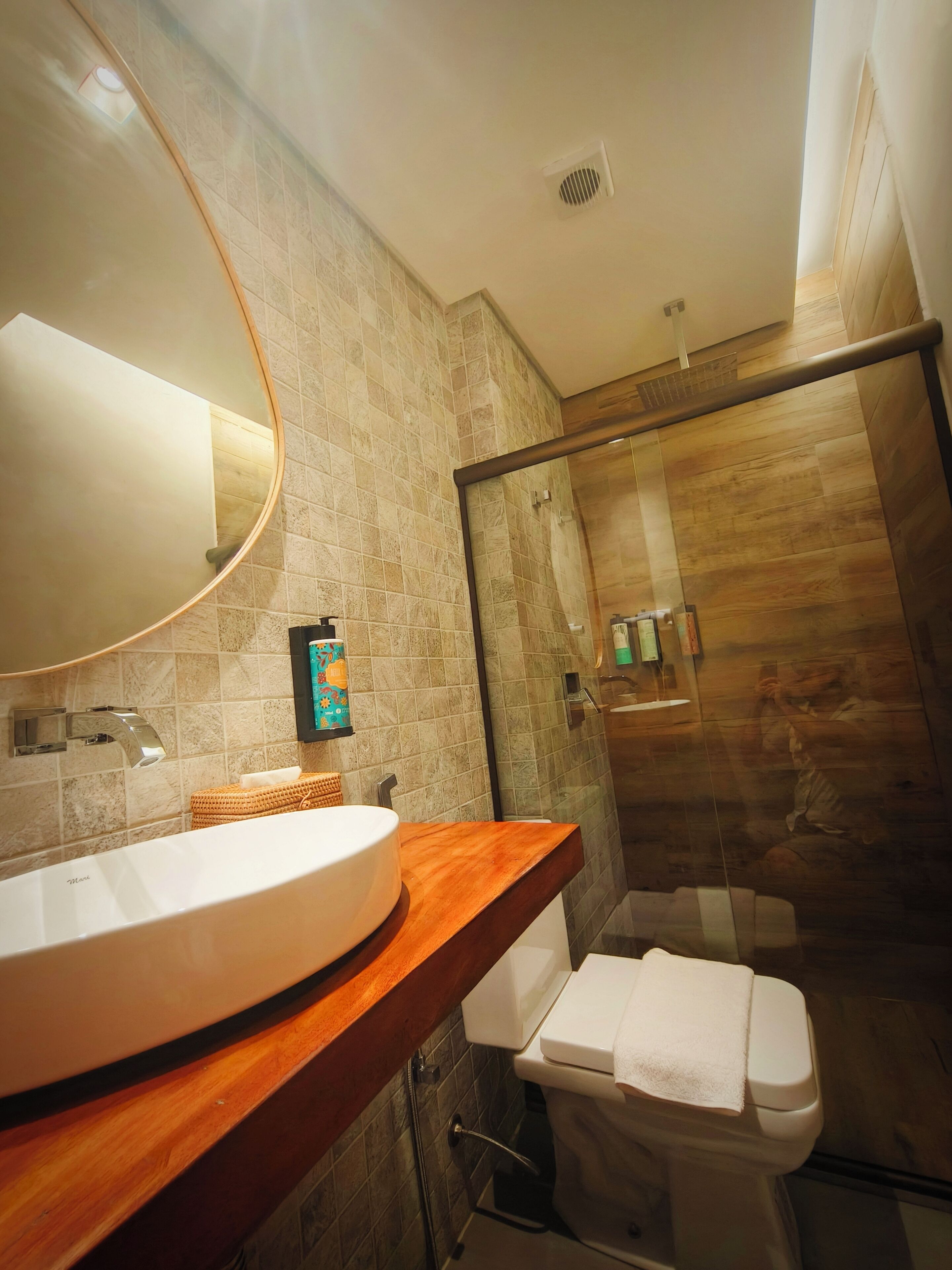 A modern bathroom with a large oval sink, a glass shower enclosure, and a wooden vanity.