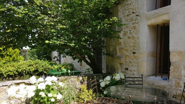 A stone building with a garden patio featuring a glass table and metal chairs. - Chic and spacious self-catered loft cottage, ideal for work or romantic getaway (SOYAUX)