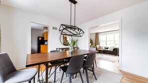 Un comedor moderno con una mesa de madera, sillas grises y una lámpara colgante de diseño geométrico.