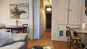 Una sala de estar acogedora con un sofá, una mesa de comedor y sillas. En la pared, un cuadro de una mujer y un toro.