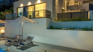 Una casa moderna de dos pisos con balcón, mobiliario exterior y piscina.