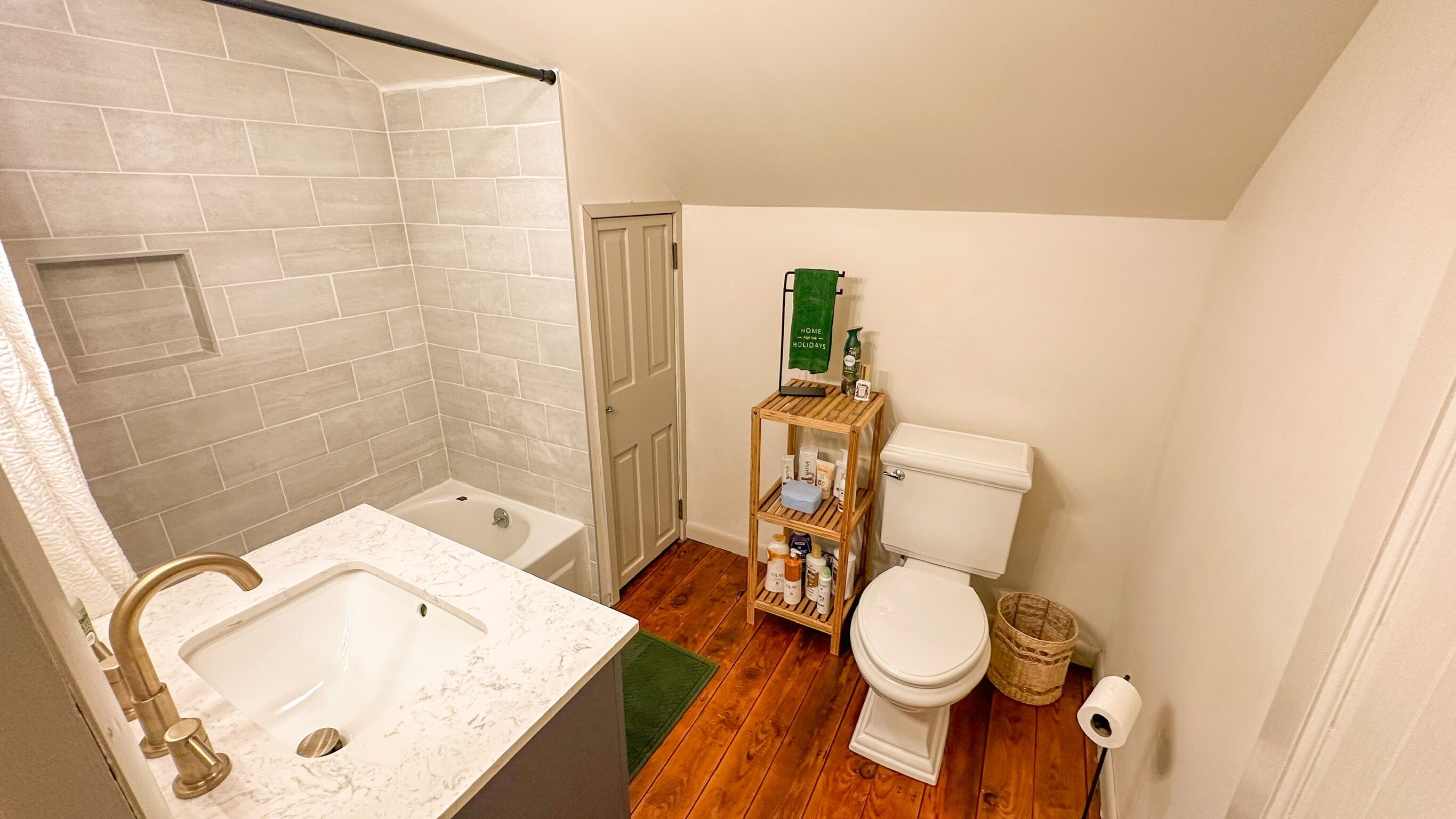 A bathroom with a bathtub, toilet, and a shelf with toiletries.