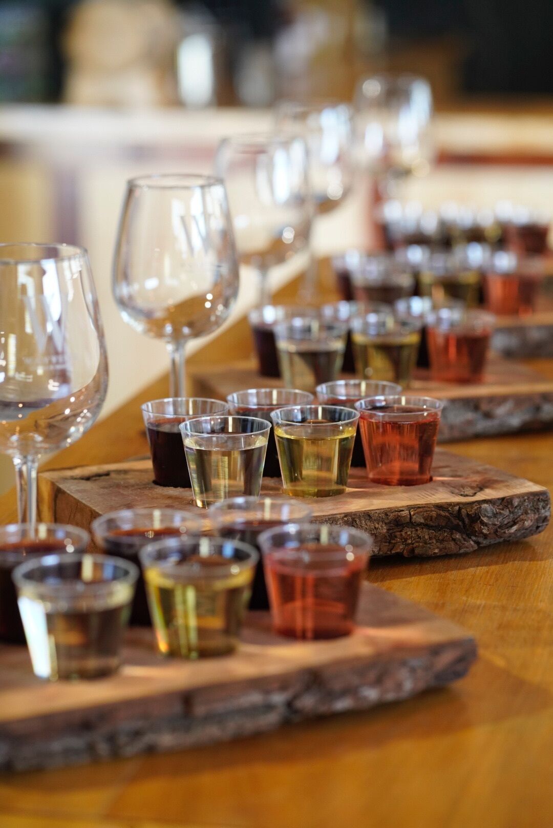 A bar setting with multiple glasses and shot glasses arranged on wooden coasters.