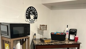 Ein kleiner Kaffeezubereich mit Mikrowelle, Kaffeemaschine und Gästebuch.