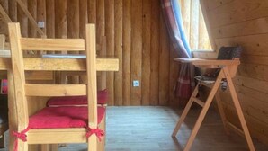 L’intérieur d’une cabane en bois, avec un lit superposé, une petite table et une pancarte « BIENVENUE » accrochée au mur.