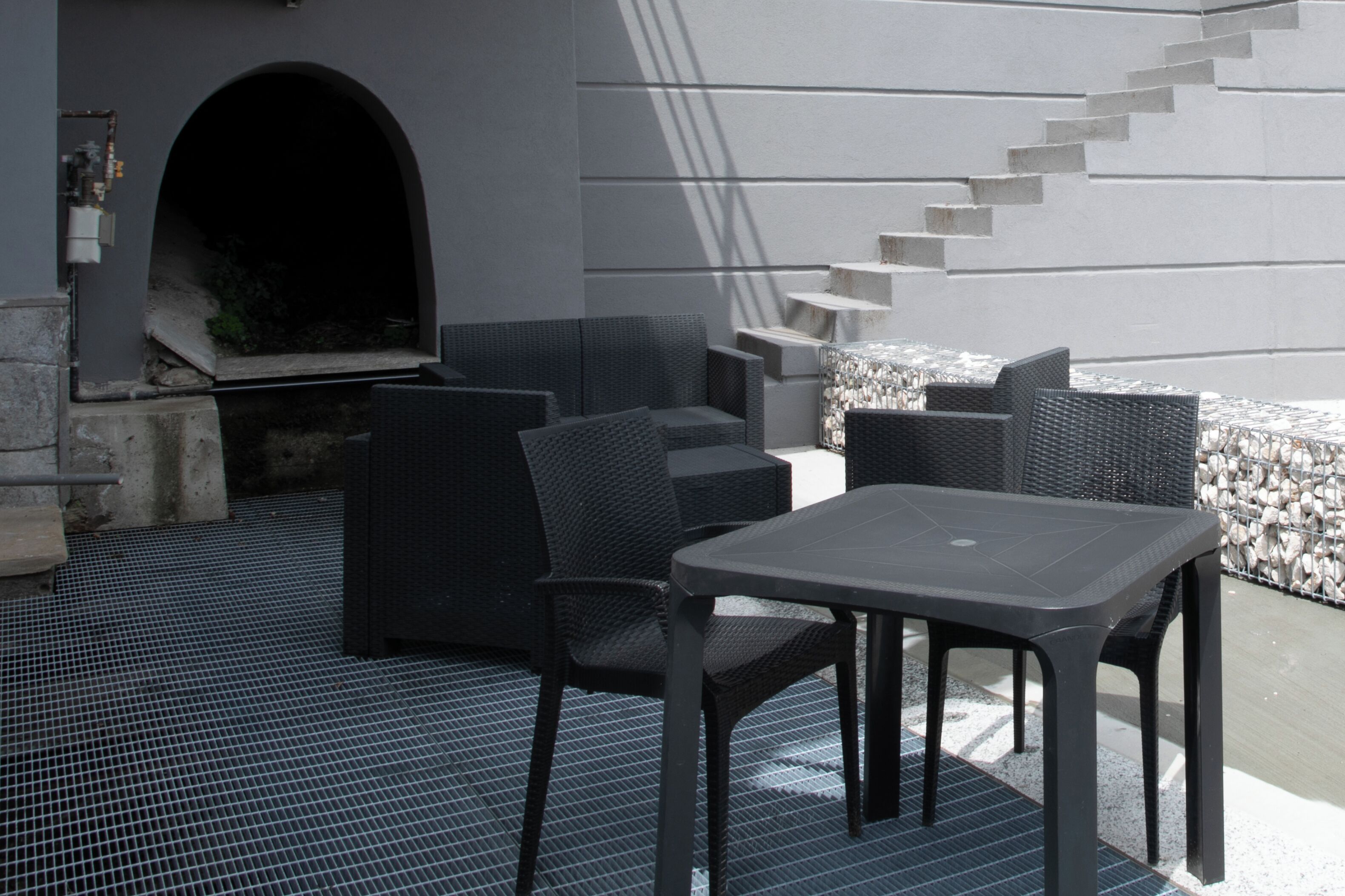 Un espace extérieur aménagé avec une table et des chaises, un mur en pierre et un escalier.