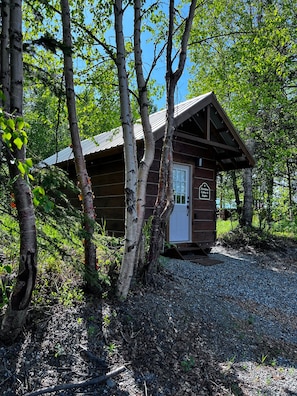 A small wooden cabin with a door and a sign indicating it is a primitive cabin.