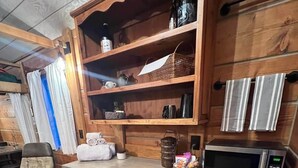 Eine Küche mit Holzausstattung, einer Mikrowelle, einem Kühlschrank und einem Stuhl.