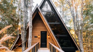 A triangular wooden cabin with a black door and a sign reading "The Lodge 610". - The UtopiA @ Paradise Lake (New Philadelphia)