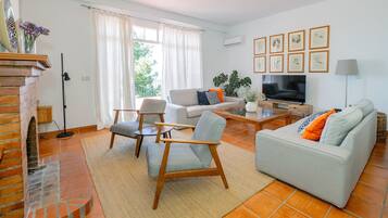 Een woonkamer met een open haard, een bank, een salontafel en een televisie.