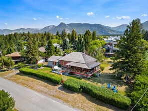 A lodge with a central building surrounded by a well-maintained lawn and a mountain backdrop. - The Barracks | Hot Tub | Walk to Beach | Historic (Windermere)