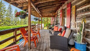 Une terrasse en bois avec des sièges extérieurs, un espace abrité et une vue sur la verdure.