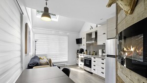 A modern kitchen with a built-in stove, white cabinets, and a large window. - The Riverbed by Suite Spot (Mont-Tremblant)