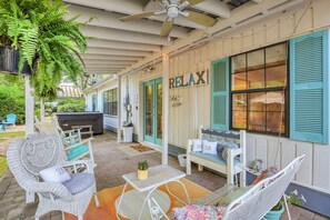 A covered patio with wicker furniture, a ceiling fan, and a 'RELAX' sign. - Charming 3BR/2Bath Beach Bungalow with Hot Tub! (Hilton Head Island)