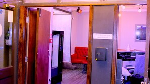 A hotel room with a red carpet, a wooden door, a check-in kiosk, a red sofa, and a desk with a computer. - Calypso Hotel Blackpool (Blackpool)