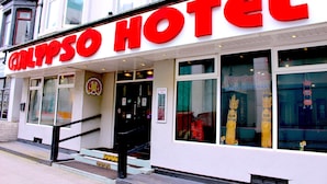 A hotel with a prominent red sign and a staircase leading to the entrance. - Calypso Hotel Blackpool (Blackpool)