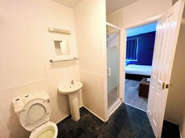 Een badkamer met toilet, wastafel en douche.