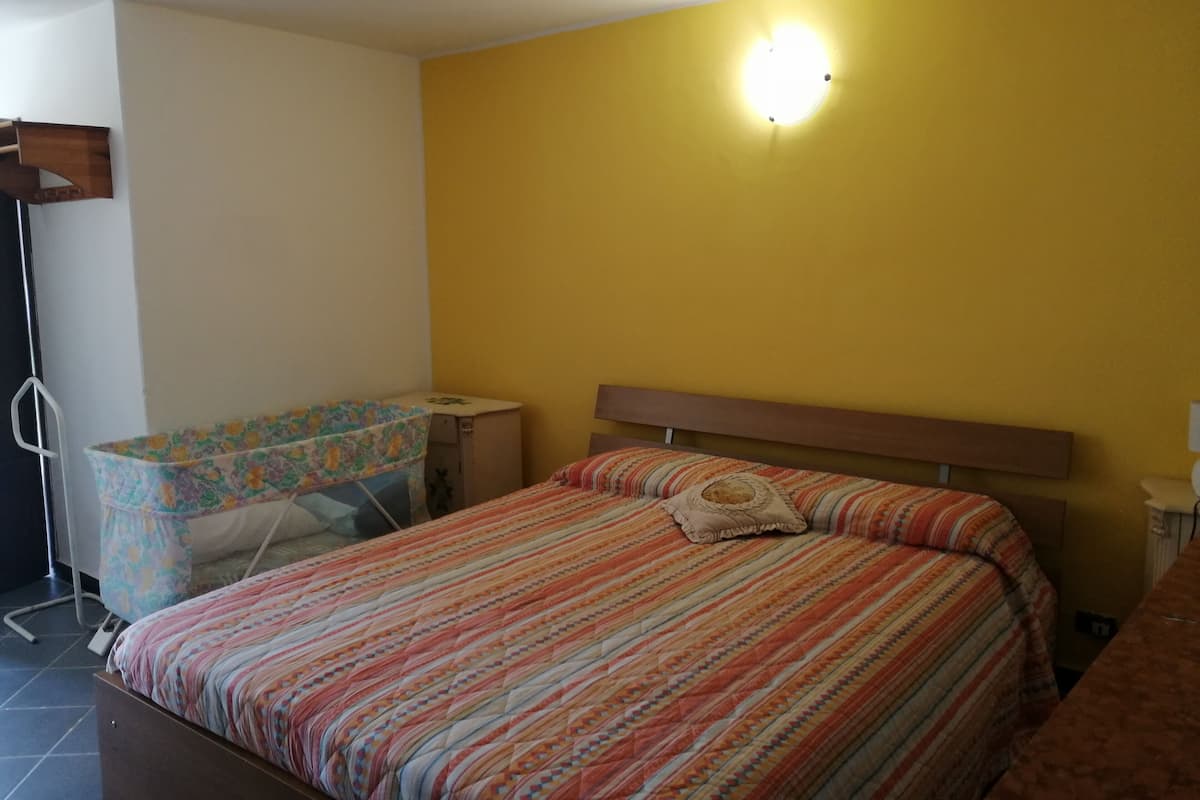 A bedroom with a bed, a bedside table, and a wall-mounted light fixture.