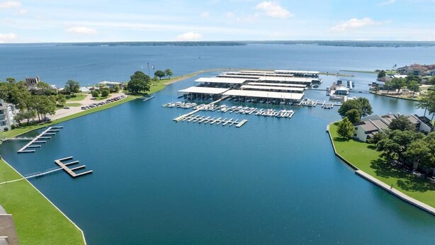 An aerial view of a marina with multiple docks and boats, surrounded by greenery and residential buildings. - Lakefront Escape with a View! Your Lake Conroe Vacation Starts Here (Montgomery)