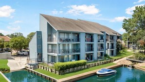 A multi-story building with balconies, a swimming pool, and a dock with a boat. - Lakefront Escape with a View! Your Lake Conroe Vacation Starts Here (Montgomery)
