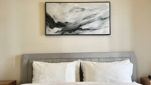 Ein Schlafzimmer mit Bett, Kopfteil und einem Wandbild im abstrakten Stil.