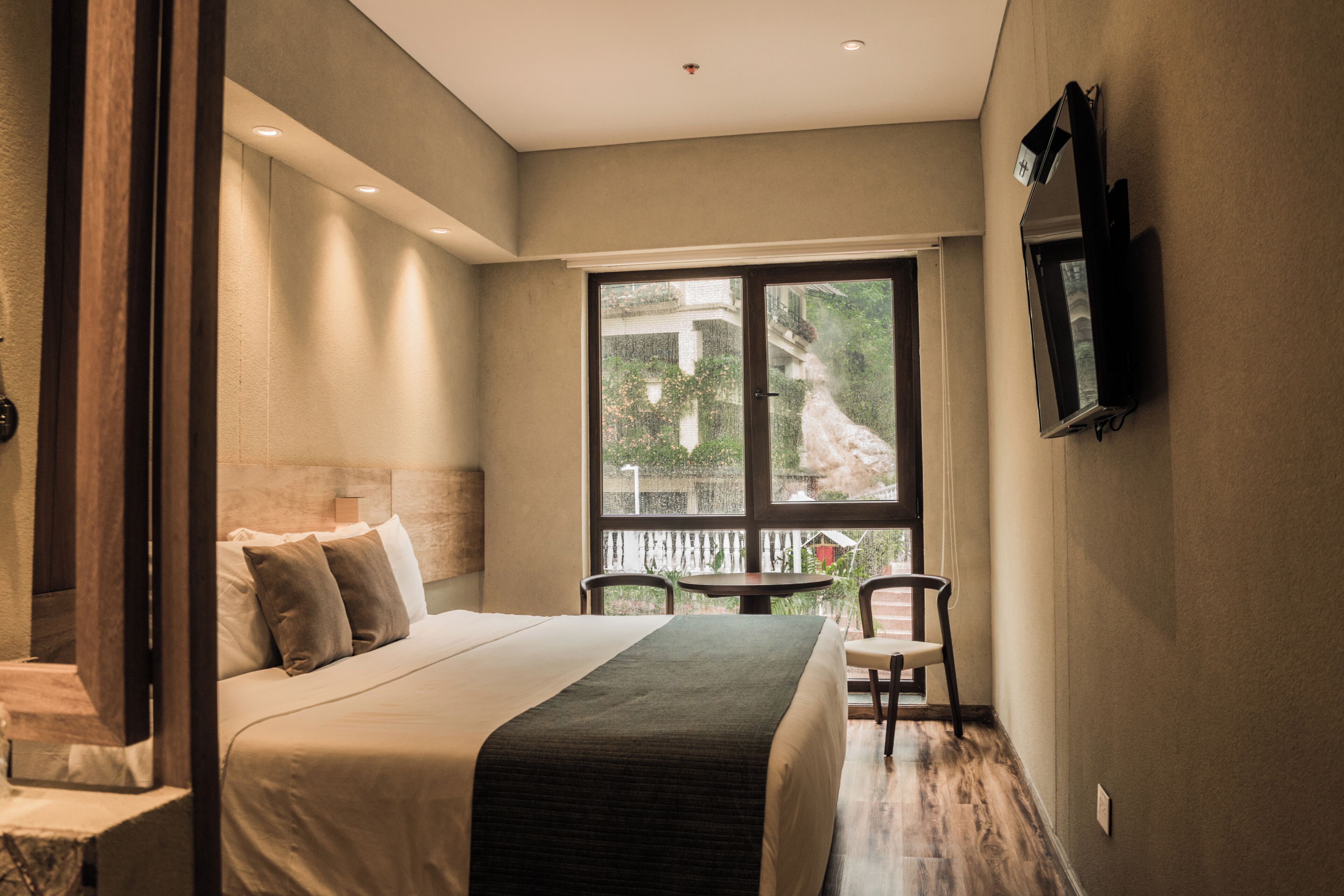 Une chambre à coucher comprenant un lit, une chaise, une table et un téléviseur fixé au mur.